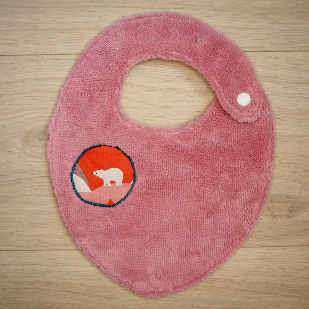 bavoir rose avec des motifs de montagnes colorées et d'ours