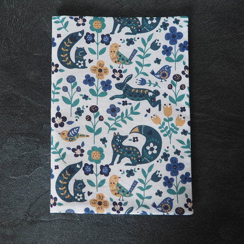 Couverture de carnet de santé aux motifs de renards, écureuils, oiseaux et plantes vert, bleu et jaune sur fond blanc. Tissu oeko-tex